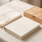 Cadeau de naissance personnalisé : 8 idées durables Coffret cadeau de naissance élégant avec textile brodé, album à couverture vierge et boîte en bois gravée de motifs décoratifs.